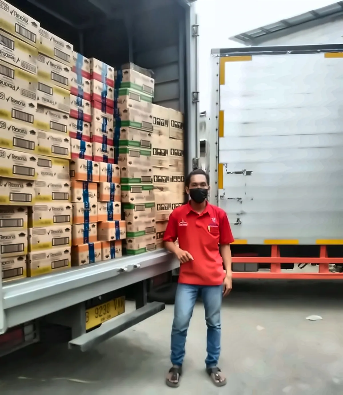 Petugas Mekar Sakti di depan muatan kardus yang tersusun di bak truk